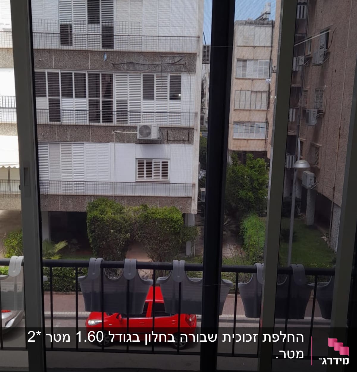 חלון זכוכית עם נוף לבניינים ורכב אדום